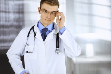 Doktor bey, gözlüklü ve steteskoplu, hastane ofisinde bekliyor. Klinikte mükemmel bir tıbbi hizmet. Tıp ve sağlık sektöründe mutlu bir gelecek