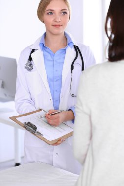 Hastane muayenehanesindeki genç kadın doktor ve hasta. Terapistin mavi renkli bluzu iyi görünüyor. Tıp ve sağlık hizmetleri kavramı