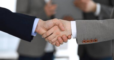 İş adamları toplantıdan ya da pazarlıktan sonra iş arkadaşlarıyla el sıkışıyorlar. Yakın plan. Modern ofisteki bir grup tanınmamış iş adamı ve kadın. Takım çalışması, ortaklık ve tokalaşma