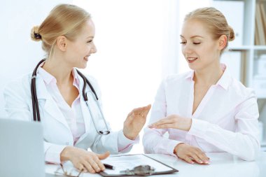 Doktor ve hasta masada otururken hastane ofisinde konuşuyorlar. Tıp alanında sağlık ve müşteri hizmetleri