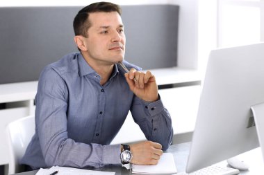 Modern ofiste bilgisayarla çalışan bir iş adamı. İş yerindeki erkek girişimcinin ya da şirket müdürünün vesikalığı. İş konsepti