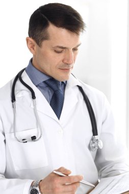 Doktor, ilaç kayıtlarını doldurmak için pano kullanıyor. Klinikte mükemmel bir tıbbi hizmet. Hastanede çalışan bir doktor. Tıp ve sağlık hizmetleri kavramları