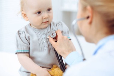 Doktor ve hasta hastanede. Küçük kız steteskopla doktor tarafından muayene ediliyor. Tıp konsepti