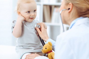 Doktor ve hasta hastanede. Küçük kız steteskopla doktor tarafından muayene ediliyor. Tıp konsepti