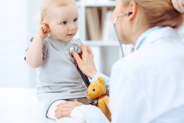 Doktor ve hasta hastanede. Küçük kız steteskopla doktor tarafından muayene ediliyor. Tıp konsepti