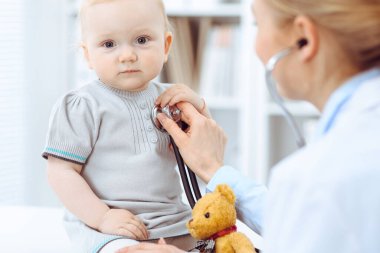 Doktor ve hasta hastanede. Küçük kız steteskopla doktor tarafından muayene ediliyor. Tıp konsepti