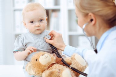 Doktor ve hasta hastanede. Küçük kız steteskopla doktor tarafından muayene ediliyor. Tıp konsepti