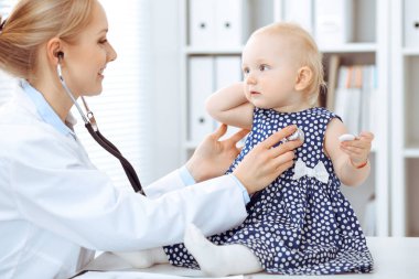Doktor ve hasta hastanede. Koyu mavi elbiseli küçük kız steteskoplu bir doktor tarafından muayene ediliyor. Tıp konsepti