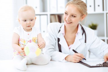 Doktor ve hasta bebek hastanede. Pembe çiçekli giyinmiş küçük kız steteskoplu bir doktor tarafından muayene ediliyor. Tıp konsepti