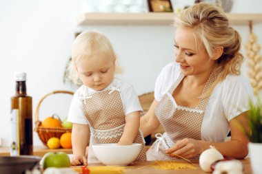 Mutfakta yemek pişiren mutlu anne ve küçük kız. Birlikte vakit geçirmek, aile eğlencesi konsepti.