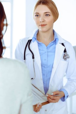 Hastane muayenehanesindeki genç kadın doktor ve hasta. Terapistin mavi renkli bluzu iyi görünüyor. Tıp ve sağlık hizmetleri kavramı