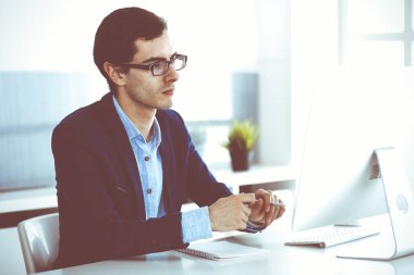 Modern ofiste bilgisayarla çalışan bir iş adamı. İş yerindeki erkek girişimcinin ya da şirket müdürünün vesikalığı. İş konsepti