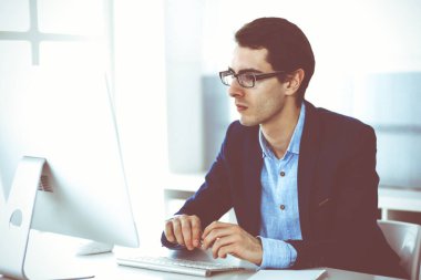 Modern ofiste bilgisayarla çalışan bir iş adamı. İş yerindeki erkek girişimcinin ya da şirket müdürünün vesikalığı. İş konsepti