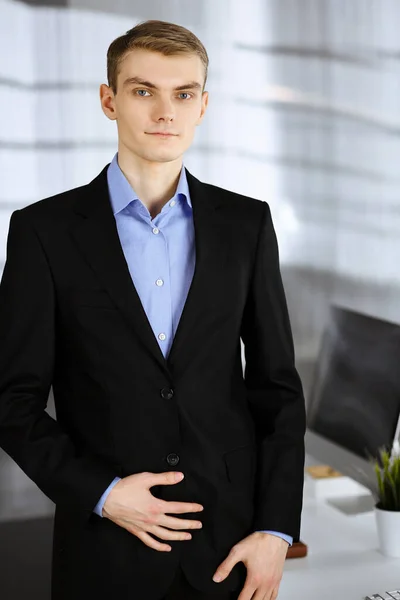 Joven hombre de negocios en un traje, mientras que de pie directamente en una oficina moderna.El éxito y el concepto de lugar de trabajo de negocios —  Fotos de Stock