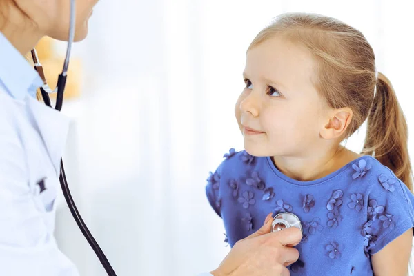 Doctor examinando a una niña por estetoscopio. Feliz niño sonriente paciente en la inspección médica habitual. Medicina y conceptos sanitarios —  Fotos de Stock