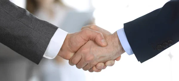 Business people shaking hands while standing with colleagues after meeting or negotiation, close-up. Group of unknown businessmen and women in modern office. Teamwork, partnership and handshake — Stock Photo, Image