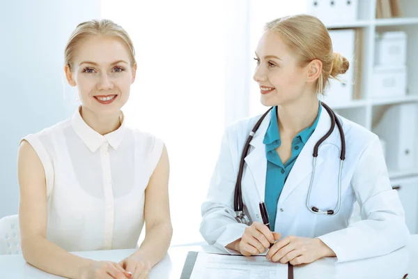 Lekarz i pacjent rozmawiają w gabinecie szpitalnym, siedząc przy biurku. Opieka zdrowotna i obsługa klienta w medycynie — Zdjęcie stockowe