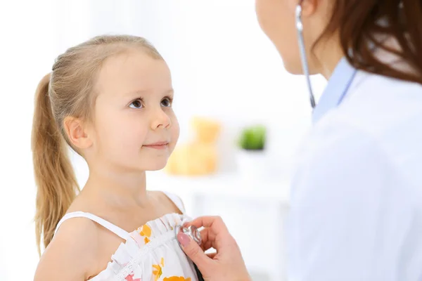 Doutor examinando uma menina por estetoscópio. Paciente de criança sorridente feliz em inspeção médica habitual. Conceitos de medicina e saúde — Fotografia de Stock