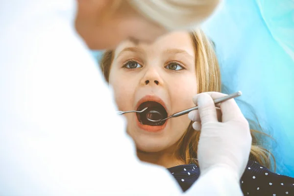 Fetița care stă pe scaunul dentar cu gura deschisă în timpul controlului oral în timp ce medicul. Vizitează cabinetul stomatologic. Conceptul de medicină. Fotografie tonată — Fotografie, imagine de stoc