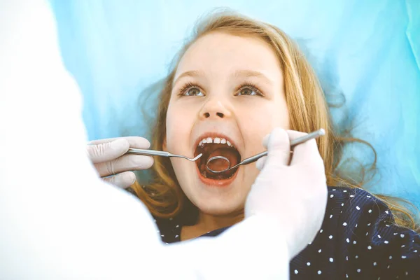 Kleine baby meisje zitten aan tandartsstoel met open mond tijdens orale check-up, terwijl de arts. Op bezoek bij de tandarts. Medicijnconcept. Getinte foto — Stockfoto