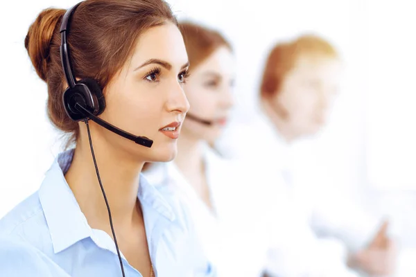 Call center operators. Focus on beautiful business woman using headset in sunny office — Stock Photo, Image