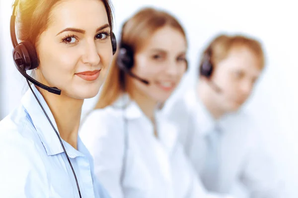 Exploitanten van callcenters. Focus op mooie zakelijke vrouw met behulp van headset in zonnig kantoor — Stockfoto