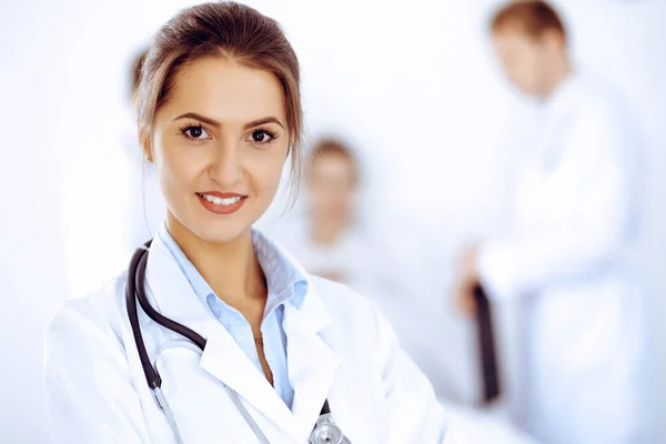 Doctora sonriendo en el fondo con paciente en la cama y dos doctores — Foto de Stock