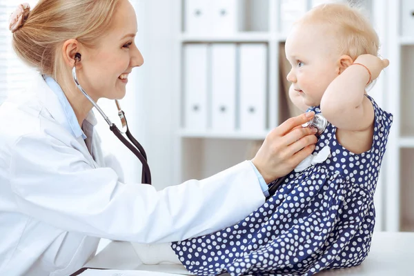 Médico y paciente en el hospital. Niña vestida con vestido azul oscuro en guisantes está siendo examinada por el médico con estetoscopio. Concepto de medicina —  Fotos de Stock