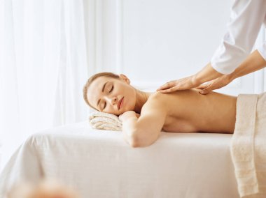Güzel bir kadın kapalı gözlerle sırt masajından hoşlanıyor. Spa tedavisi kavramı
