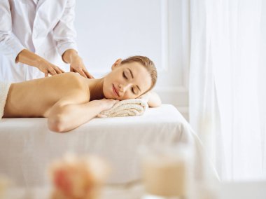 Güzel bir kadın kapalı gözlerle sırt masajından hoşlanıyor. Spa tedavisi kavramı