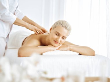 Güzel sarışın kadın kapalı gözlerle sırt masajından hoşlanıyor. Spa salonu konsepti