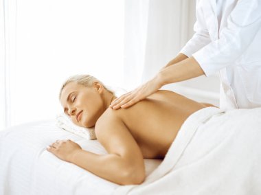Güzel sarışın kadın kapalı gözlerle sırt masajından hoşlanıyor. Spa salonu konsepti