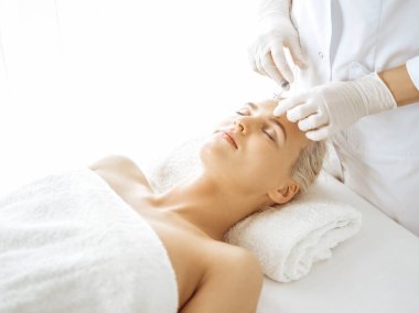 Güzellik uzmanı elleri şırıngayla kadın yüzüne güzellik prosedürü uyguluyor. Kozmetik tıp ve cerrahi, güzellik enjeksiyonları konsepti