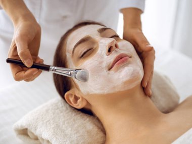 Güzel esmer kadın kapalı gözlerle kozmetik maske takmaktan zevk alıyor. Tıp ve kaplıca merkezi kavramlarında rahatlatıcı tedavi