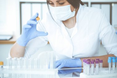 Koruyucu gözlüklü profesyonel kadın bilim adamının laboratuarda reaktörlerle deney yapması. Tıp ve araştırma konsepti