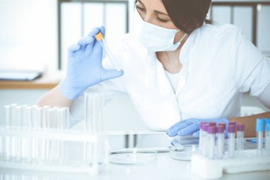 Koruyucu gözlüklü profesyonel kadın bilim adamının laboratuarda reaktörlerle deney yapması. Tıp ve araştırma konsepti