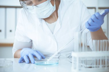 Koruyucu gözlüklü profesyonel kadın bilim adamının laboratuarda reaktörlerle deney yapması. Tıp ve araştırma konsepti