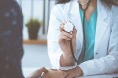 Elinde steteskop olan bir doktor. Doktor kadın hastasını muayene etmeye hazır..