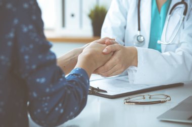 Doktorun kadın hastasına güvence verdiği yakın plan. Tıbbi etik ve güven kavramı
