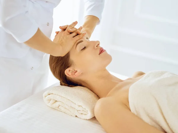 Красива жінка насолоджується масажем обличчя з закритими очима. Концепція спа-лікування в медицині — стокове фото