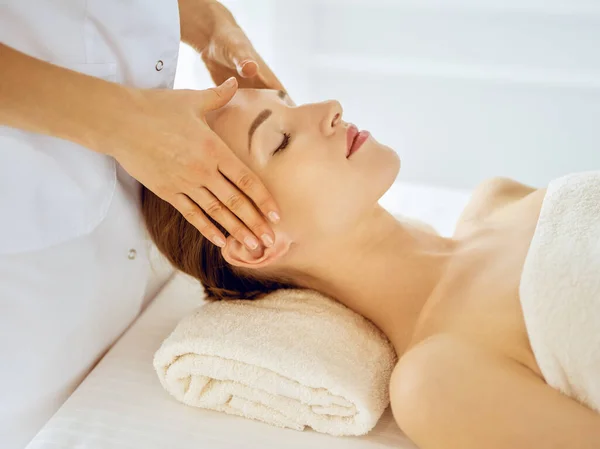 Hermosa mujer disfrutando de masaje facial con los ojos cerrados. Concepto de tratamiento de spa en medicina — Foto de Stock