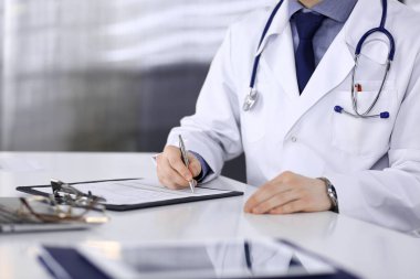 Bilinmeyen erkek doktor, klinikteki ilaç geçmişi kayıtlarıyla birlikte yakın planda oturuyor. İşteki genç doktor. Mükemmel sağlık hizmeti, tıp konsepti