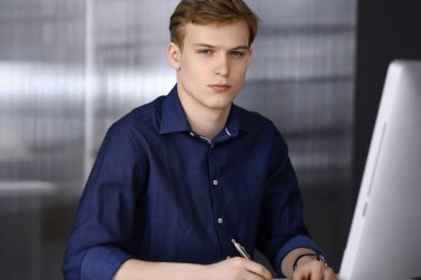 Bilgisayarla çalışan genç sarışın iş adamı. Girişim işi, başarı için çok çalışmak ve zamanın dışında çalışmak demektir.