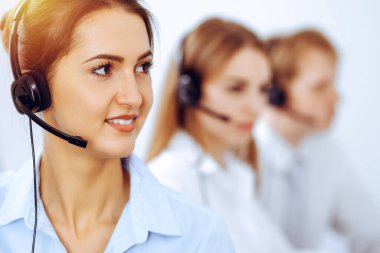 Merkez operatörlerini ara. Güneşli ofiste kulaklık kullanan güzel bir iş kadınına odaklan.