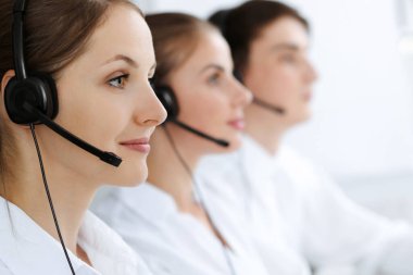 Merkezi ara. Güzel genç bir kadın müşterilere yardım etmek için kulaklık ve bilgisayar kullanıyor. İş konsepti