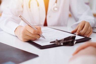 Bilinmeyen kadın-doktor hastaya danışmanlık yaparken başvuru formu dolduruyor. güneşli oda tıp konseptinde