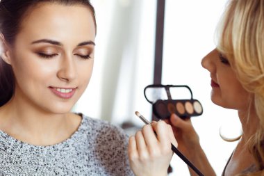 Profesyonel makyöz güzel genç bir kadınla çalışıyor. Gelin, moda ya da çıplak stil