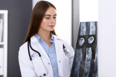 Doktor kadın hastanenin penceresinin yanında dikilirken röntgen filmini inceliyor. Cerrah ya da ortopedist. Tıp ve sağlık hizmetleri kavramı