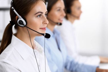 Merkezi ara. Bir grup operatör iş başında. Kulaklıklı güzel iş kadınına odaklan.