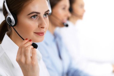 Merkezi ara. Bir grup operatör iş başında. Kulaklıklı güzel iş kadınına odaklan.